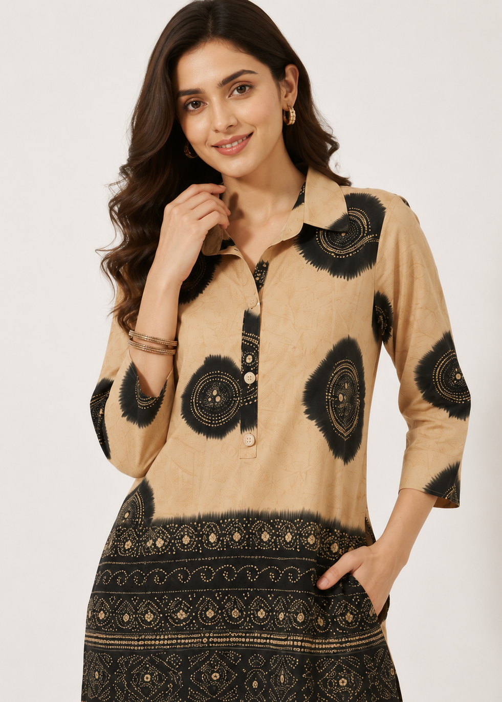 A woman modeling a beige and black printed kurta with a collar, button placket, and patterned hem against a plain light background.