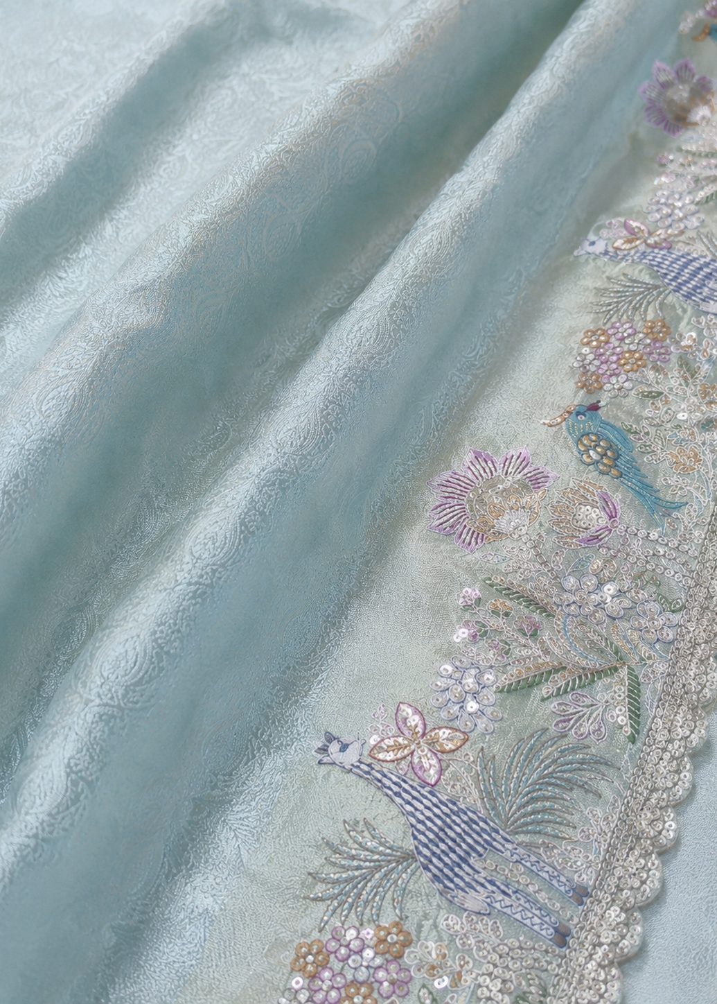 Close-up of embroidered fabric with floral patterns on a light blue background