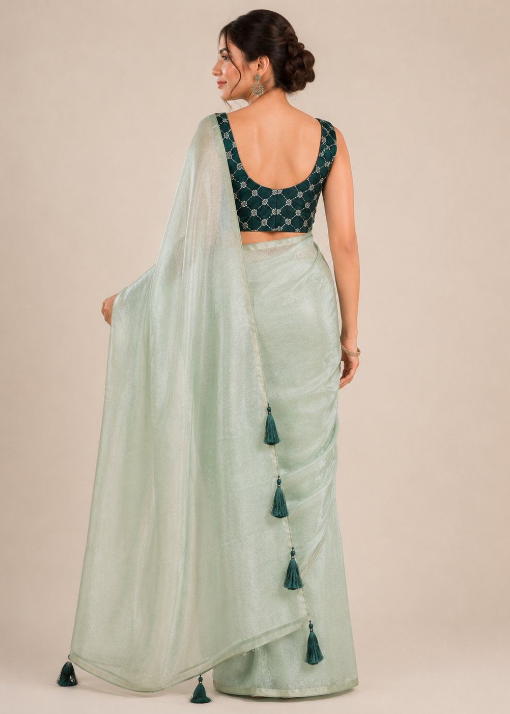 Woman wearing a light green saree with a dark green blouse against a beige background