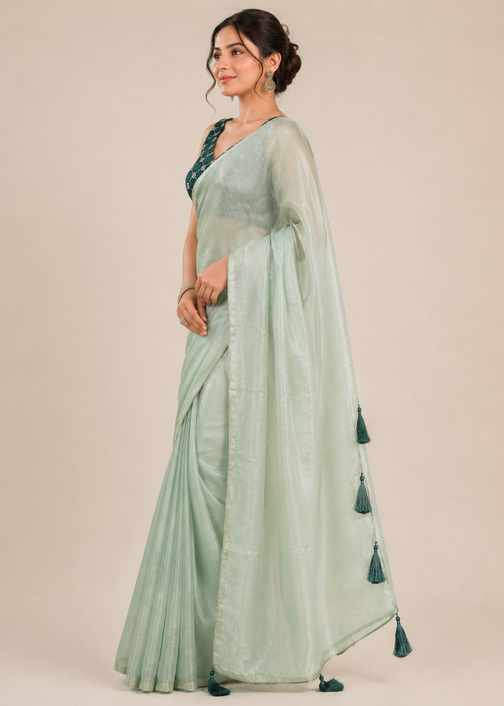 Woman wearing a light green saree with a plain background