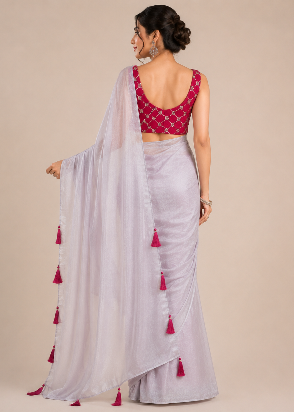 Woman wearing a light gray saree with red blouse and tassels on a beige background