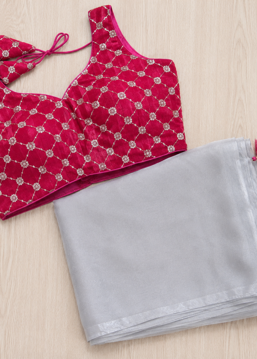 Red blouse with silver patterns and a gray saree with red tassels on a light wooden surface