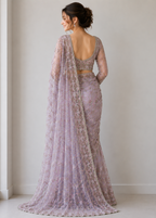 Woman wearing a purple lace saree with a plain background