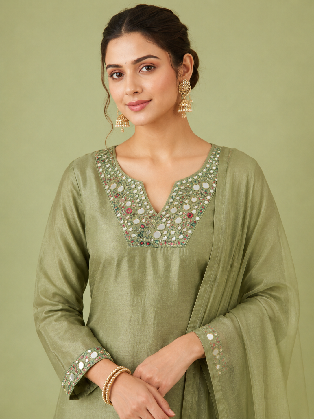 Woman wearing a green traditional outfit with intricate detailing on a light green background