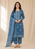 Woman wearing a blue embroidered traditional outfit with a beige background
