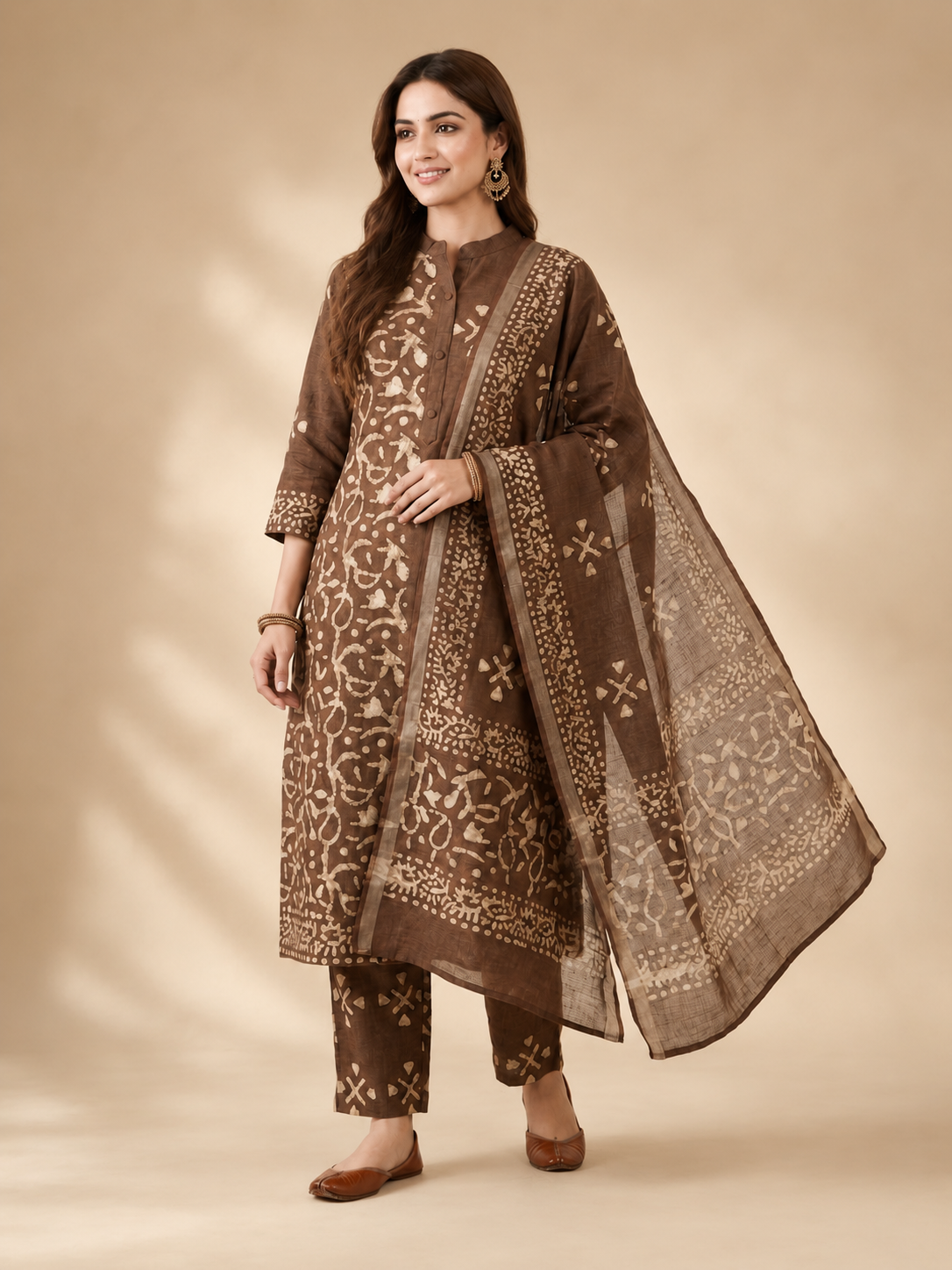 Woman wearing a brown traditional outfit with a matching dupatta on a beige background