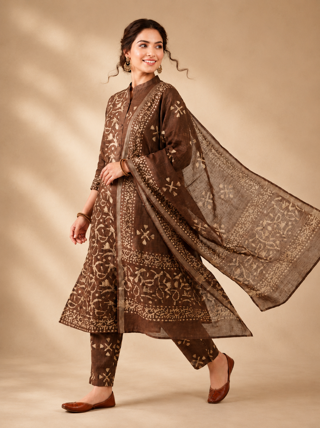Woman wearing a brown traditional outfit with a matching dupatta on a beige background