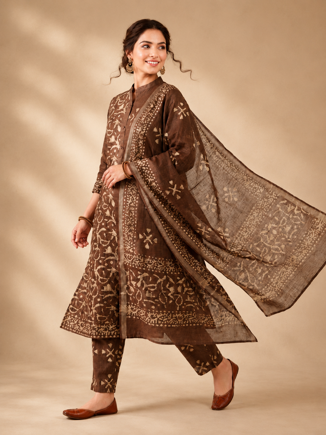 Woman wearing a brown traditional outfit with a matching dupatta on a beige background