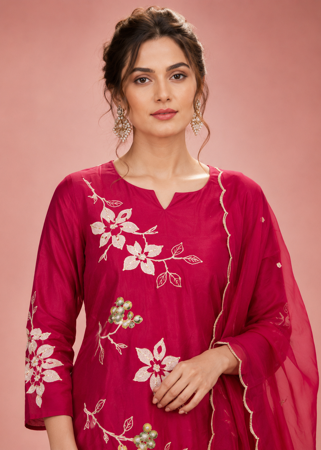 Woman wearing a pink embroidered traditional outfit on a pink background