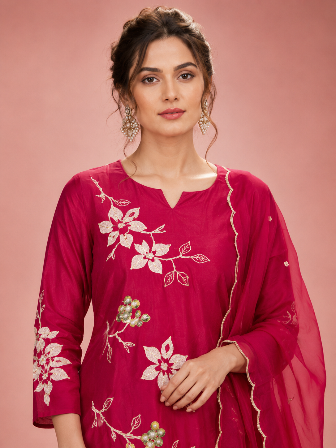 Woman wearing a pink embroidered traditional outfit on a pink background