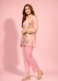 Woman wearing a pink outfit with a floral jacket against a pink background