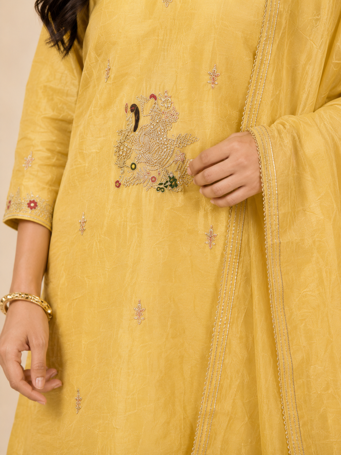 Yellow embroidered garment with intricate designs on a plain background