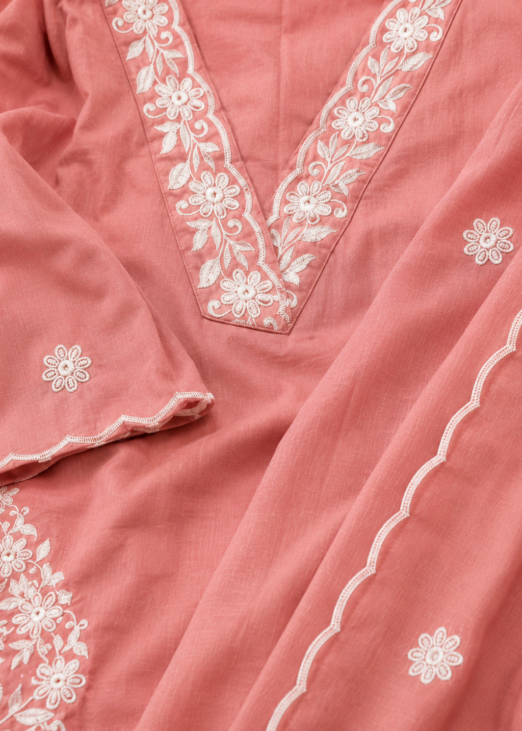 Close-up of a pink fabric with white floral embroidery