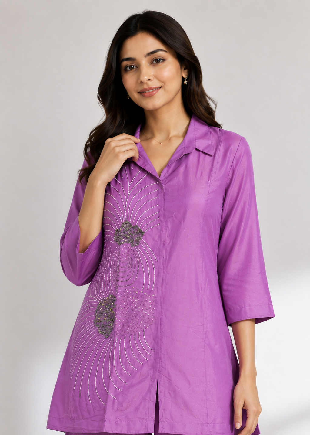A woman modeling a purple three-quarter sleeve kurta with silver sequin embroidery on the front, paired with matching purple trousers, against a light gray studio background.