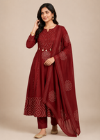 Woman wearing a maroon traditional outfit with intricate patterns on a beige background