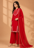 Woman wearing a red embroidered outfit with a beige background