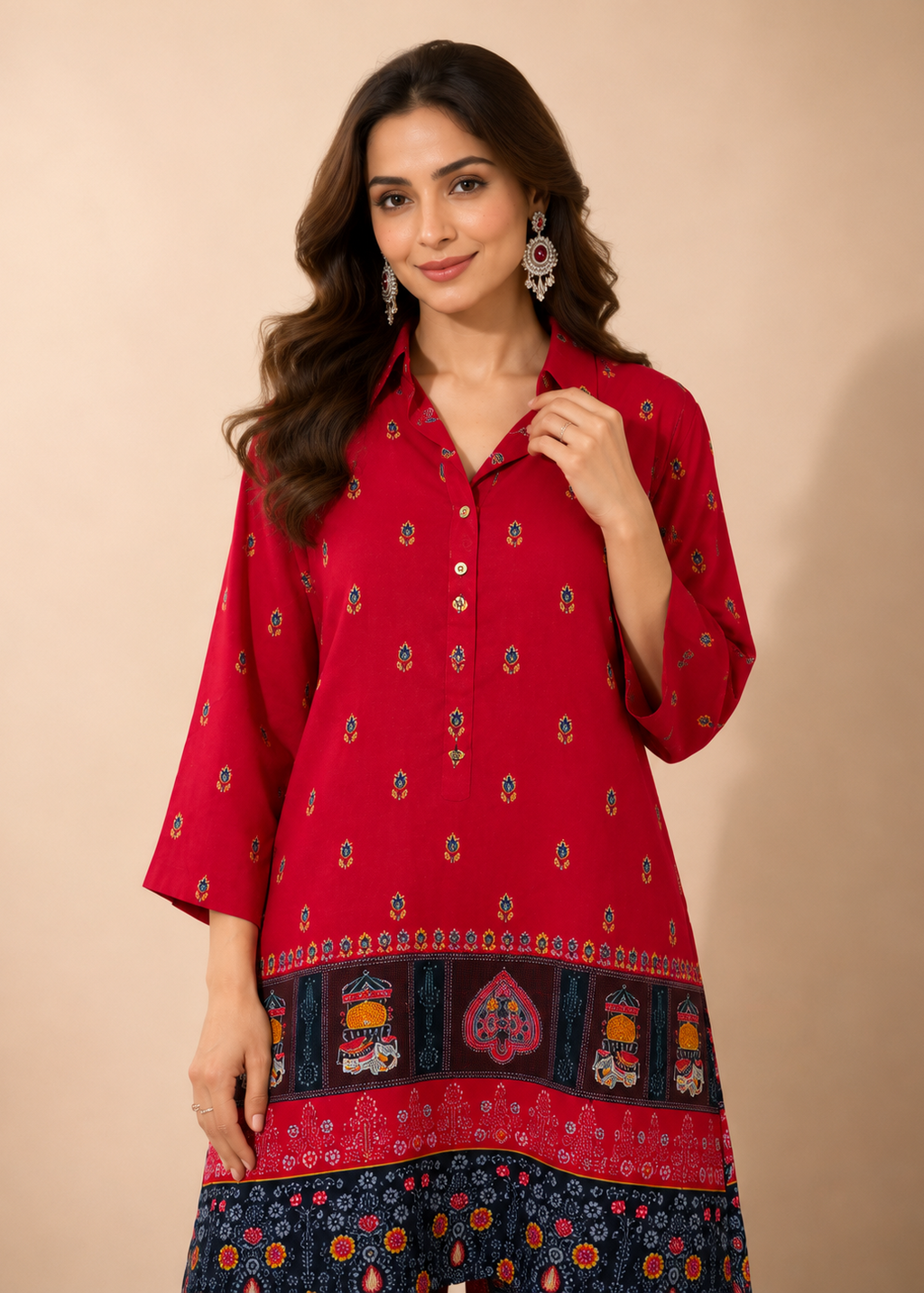 A woman modeling a red three-quarter sleeve kurta with small colorful printed motifs and a decorative border, paired with a navy patterned bottom, against a solid beige background.