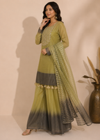 A woman models a traditional Indian outfit consisting of an olive green kurta with gold embroidery, wide-leg pleated pants with a dark-to-light gradient, and a matching sheer dupatta with gold patterns.