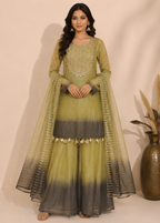 A woman models a traditional Indian outfit consisting of a sage green and dark gray ombre flared kurta with matching sheer dupatta, set against a plain beige background.