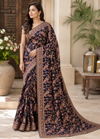 Woman wearing a traditional saree in an outdoor setting with plants and lanterns.