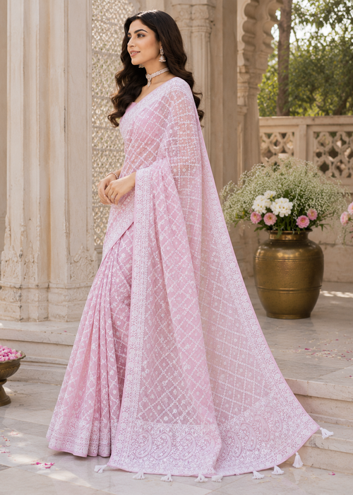 Woman in a pink saree standing outdoors with decorative elements.