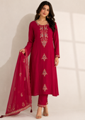 A woman models a deep magenta pink ethnic suit set featuring a long kurta with gold embroidery, matching pants, and a coordinating dupatta, set against a neutral studio background.