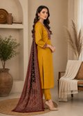 Woman in a yellow traditional outfit with a patterned scarf standing in a room with decor elements.