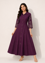 A woman modeling a long, dark purple button-front dress with lace embroidered three-quarter sleeves, standing against a plain off-white studio background.