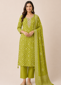 A woman modeling a lime green traditional Indian salwar kameez suit with matching dupatta. The kurta features vertical diagonal stripes and silver mirror work embroidery on the neckline, paired with matching green trousers and a coordinating patterned dupatta, set against a solid beige background.