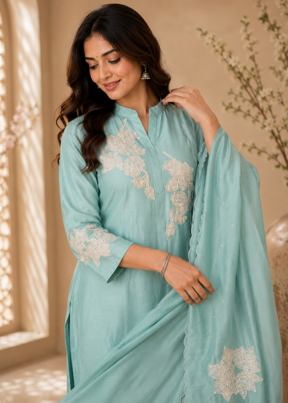 Woman wearing a light blue embroidered traditional outfit indoors.