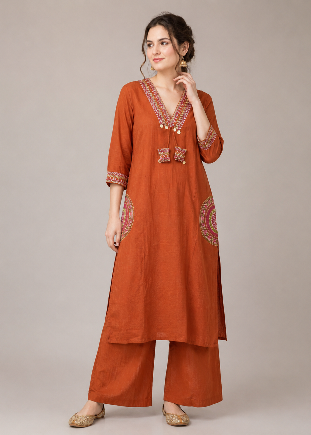Woman wearing a rust-colored traditional outfit with intricate patterns on a plain background