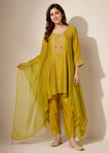 A woman models a three-piece olive green ethnic suit set featuring a long tunic with gold embroidery, matching trousers, and a sheer dupatta, set against a plain beige background.