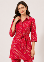 A woman modeling a red three-quarter sleeve shirt dress with a white geometric pattern, featuring a button-down front, pointed collar, and a matching tie belt at the waist, set against a plain light background.
