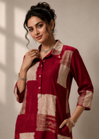 A woman modeling a red and beige patchwork kurta with a button-down front and three-quarter sleeves, set against a neutral beige background with soft window shadows.
