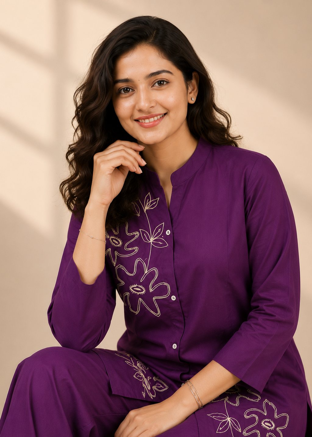 A woman wearing a purple traditional kurta set with white floral embroidery, posing against a warm beige background with soft shadow overlays.