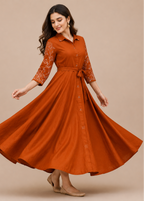 A woman modeling a rust-orange midi dress with lace three-quarter sleeves and a matching waist tie, captured mid-spin against a solid beige studio background.