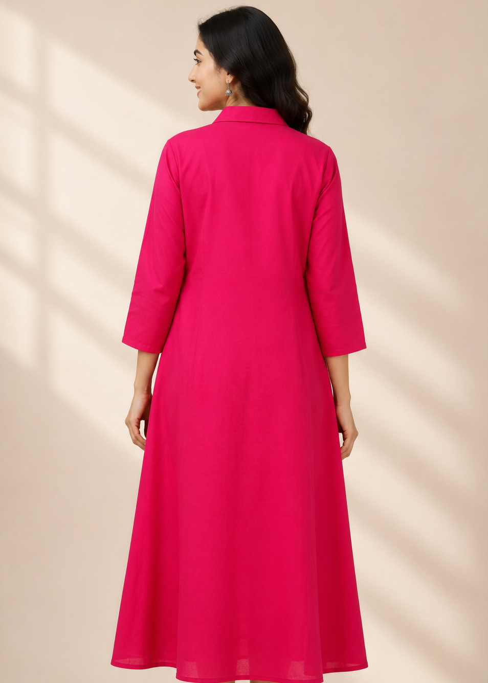 A woman wearing a bright pink midi dress, shown from the back. The dress has three-quarter sleeves, a collar, and a straight, flowing silhouette.