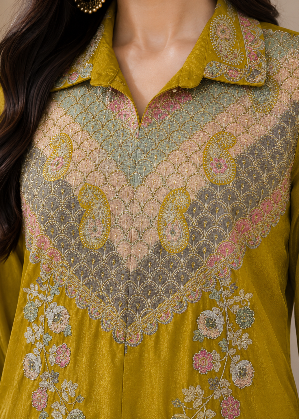A close-up of a mustard yellow embroidered kurta featuring a V-shaped yoke with intricate paisley and floral patterns in beige, pink, and light blue, paired with a matching collar.