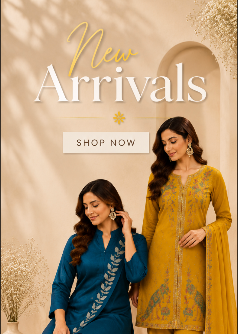 Two women modeling traditional South Asian salwar kameez sets in a warm beige studio setting with decorative dried flowers and arches. One woman wears a deep teal blue set with silver embroidery, and the other wears a mustard yellow set with blue floral embroidery and a matching dupatta.