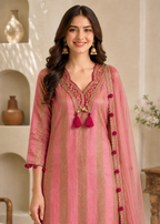A woman modeling a pink and gold striped kurta with a matching sheer dupatta, featuring detailed gold embroidery on the neckline and red tassel accents.